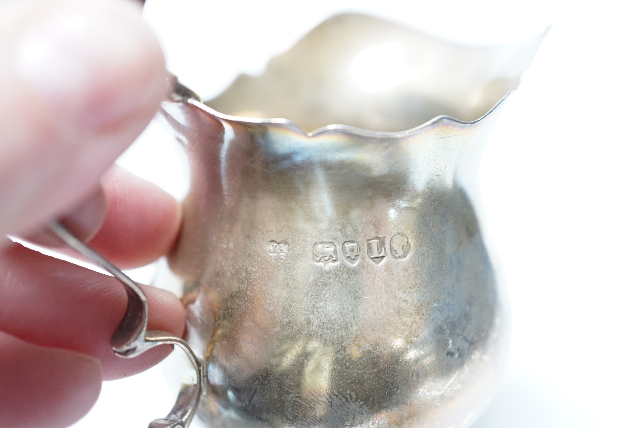 A Victorian silver inverted pyriform cream jug, London, 1886, 10.4cm, another, embossed, Chester, 1896 and an Edwardian silver embossed christening mug, Chester, 1902, 8.1oz.